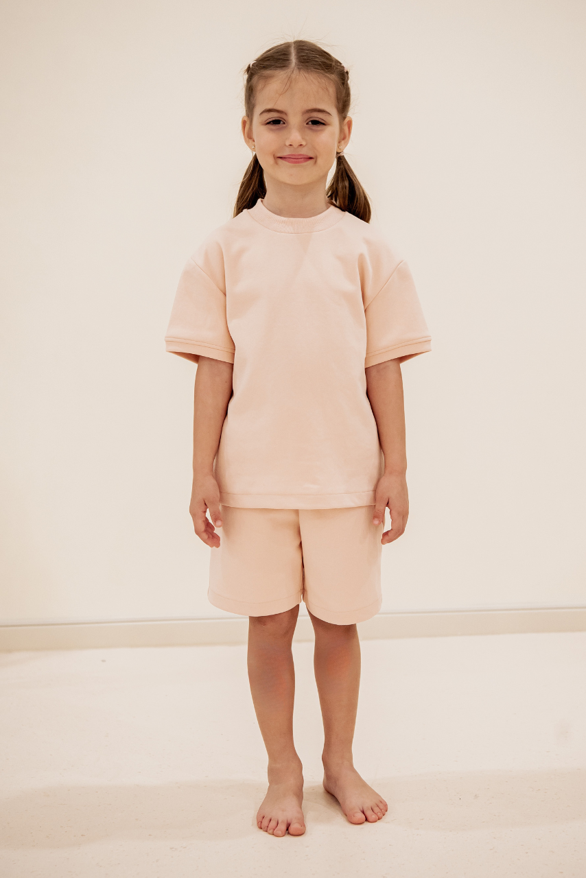 Child wearing Little Yogi yoga uniform — Peach T-shirt and shorts during class